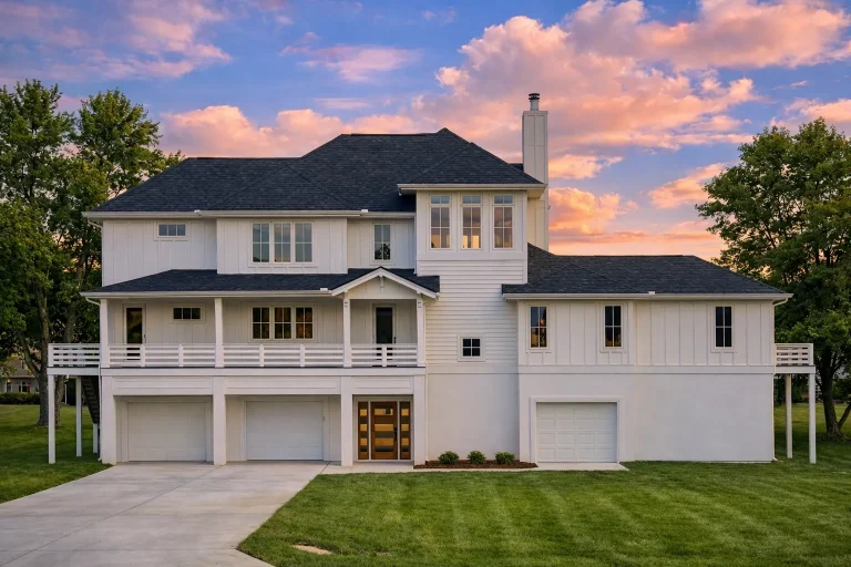 Front elevation of a Transitional Modern Farmhouse featuring stone accents, horizontal siding, board and batten details, and a three-car garage with elevated entry steps