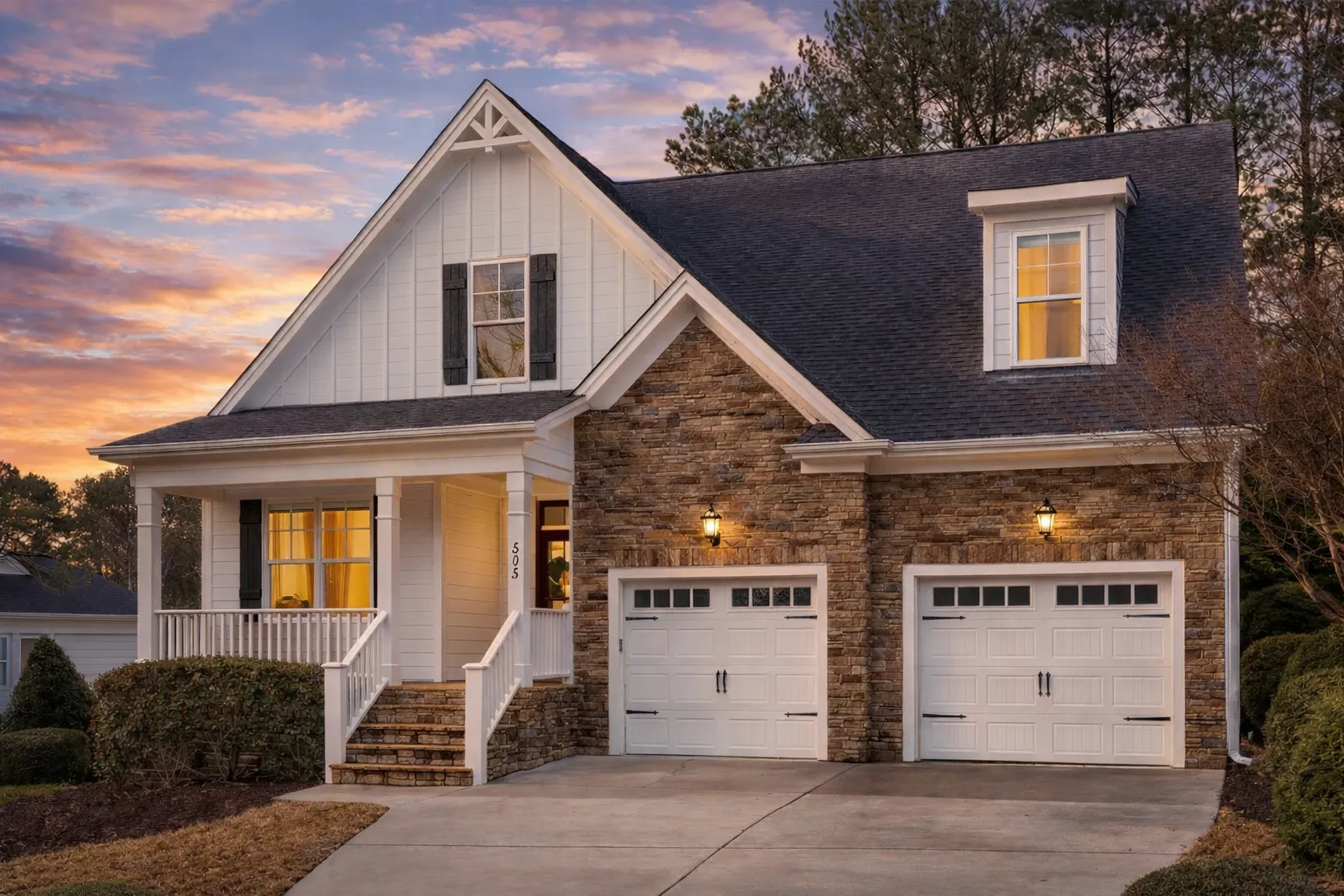 Front exterior view of a modern farmhouse style home featuring board and batten siding, steep gable roof, covered porch, and attached two-car garage