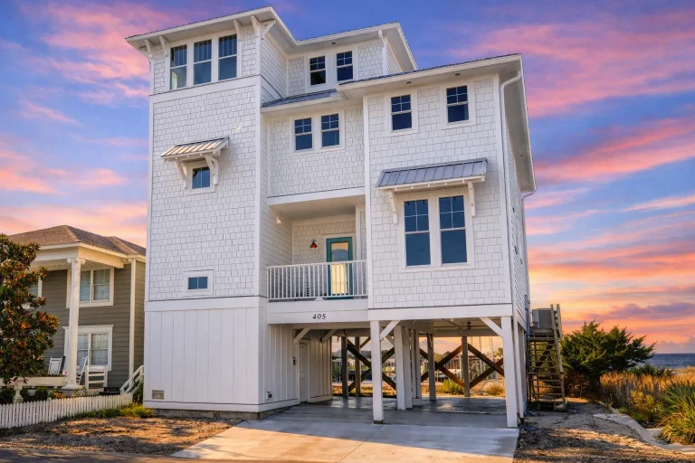 Front elevation of coastal Low Country style home with elevated foundation, horizontal lap siding, covered porch, and metal roof
