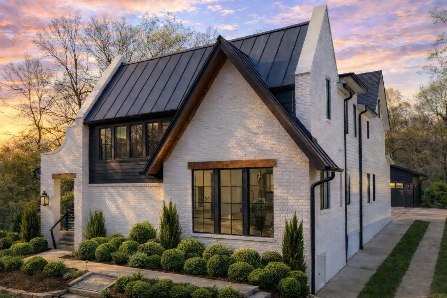 Front exterior of a Modern Farmhouse home featuring white painted brick, dark metal roof, and black-framed windows
