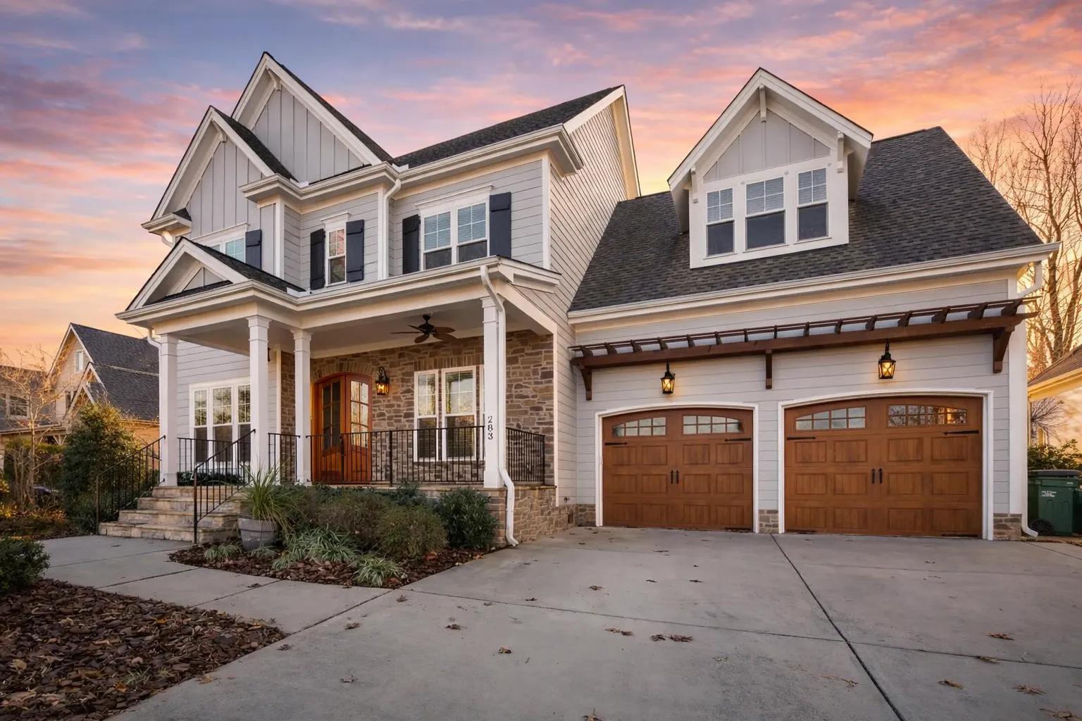 Front elevation of Traditional Colonial style home with horizontal lap siding, brick water table accent, gabled rooflines, and attached two-car garage