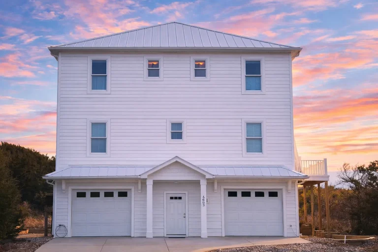 Front elevation of a Coastal Traditional garage apartment with horizontal siding, two-car garage, and balanced three-story design