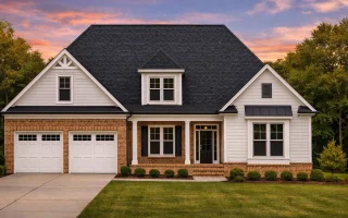 Front elevation of a Traditional Craftsman style home featuring stone accents, shake siding, and a two-car garage beneath a steep gable roof
