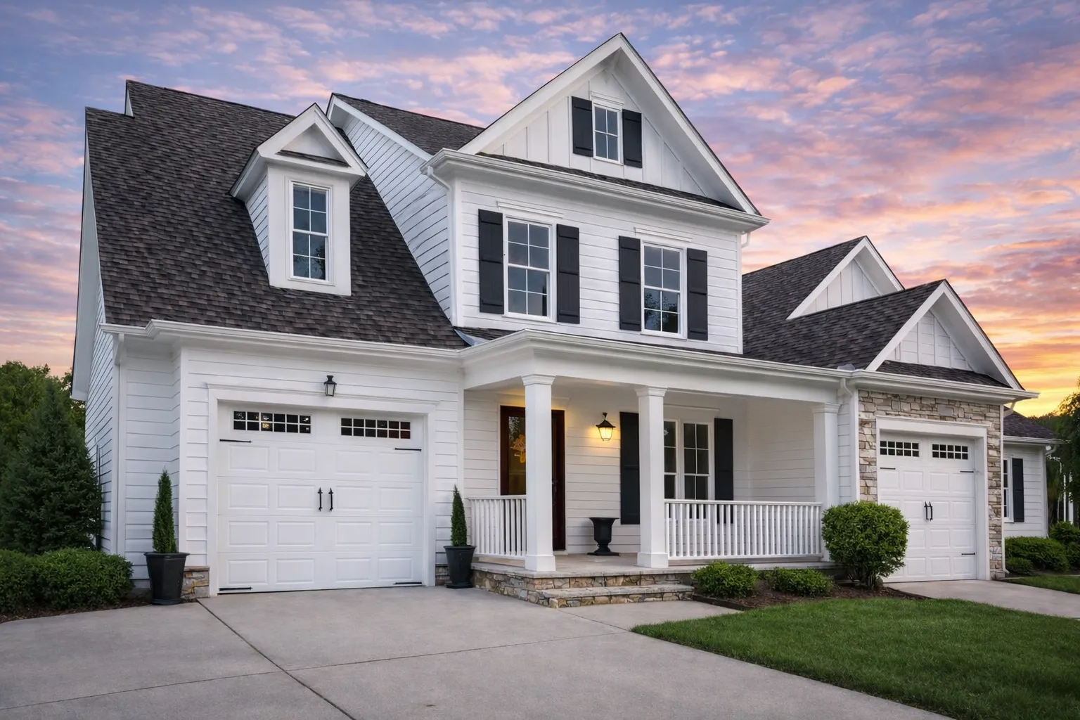 Front elevation of a Traditional Neo-Colonial suburban home featuring horizontal siding, covered front porch, symmetrical windows, and double garage
