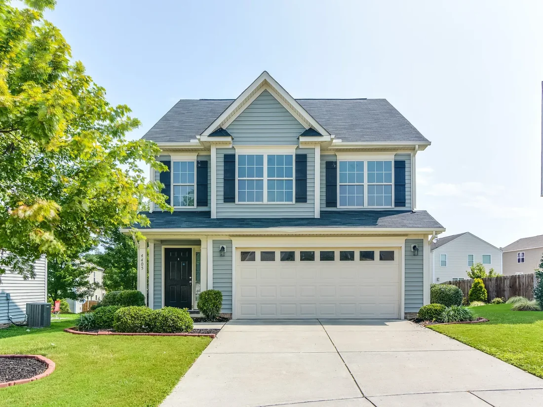 Front elevation of a Traditional Colonial style home featuring a balanced two-story design with horizontal siding, stone accents, and black shutters.