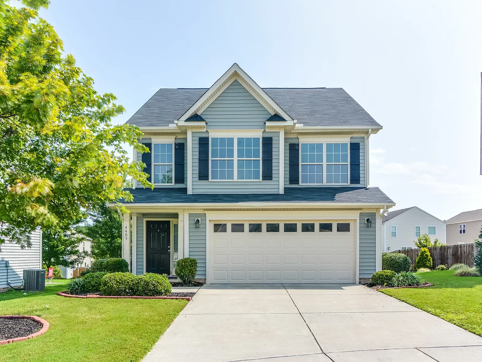 Front elevation of a Traditional Colonial style home featuring a balanced two-story design with horizontal siding, stone accents, and black shutters.