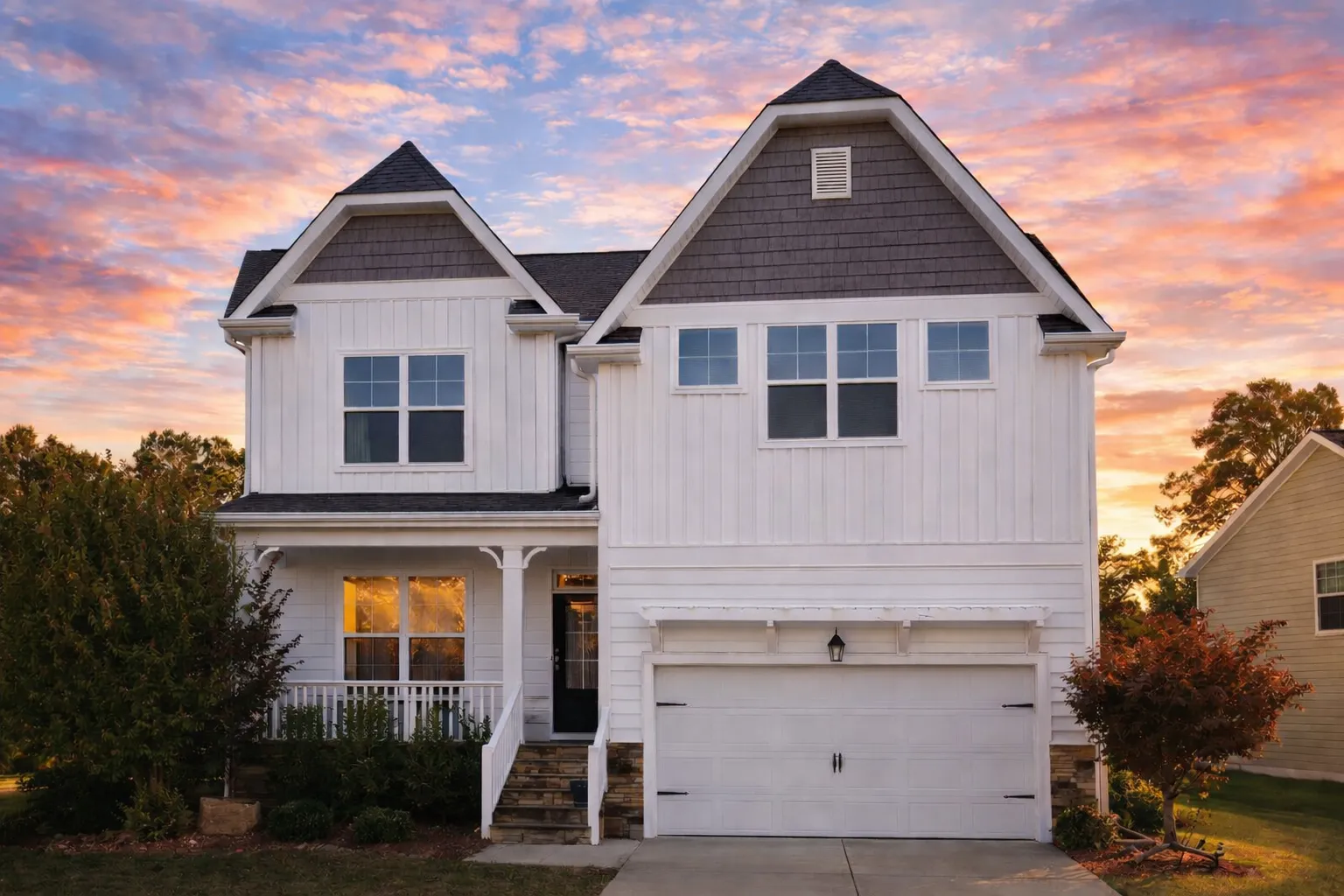 Front view of a Tudor Revival style home featuring stone base, horizontal siding, stucco panels, and decorative half-timbering for classic charm