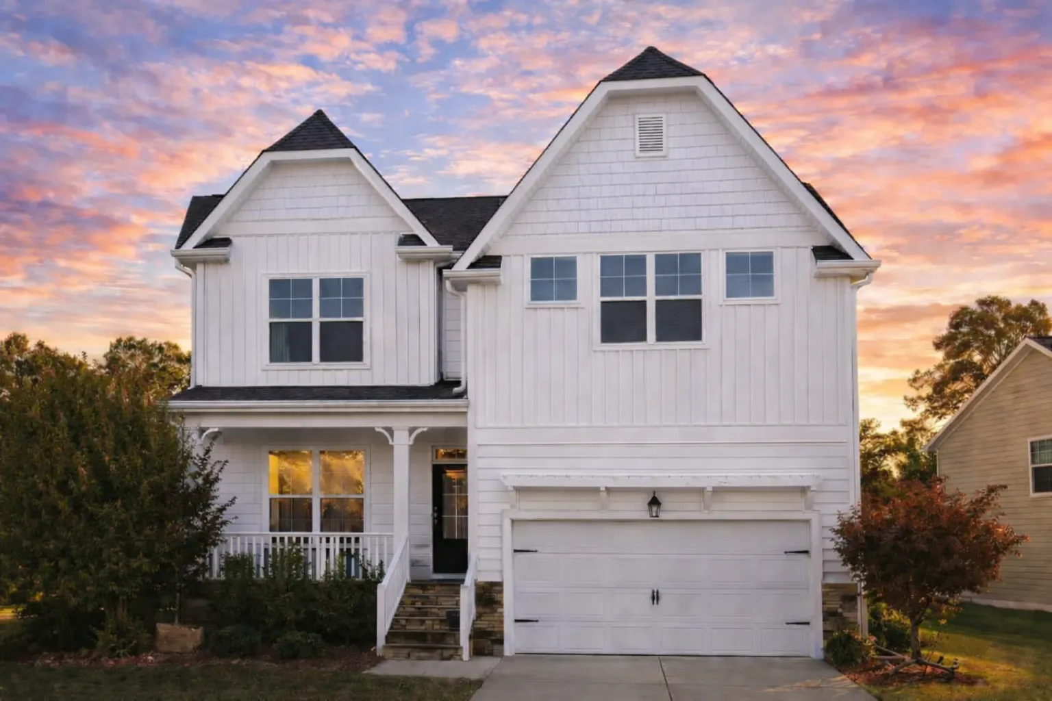 Front view of a Tudor Revival style home featuring stone base, horizontal siding, stucco panels, and decorative half-timbering for classic charm
