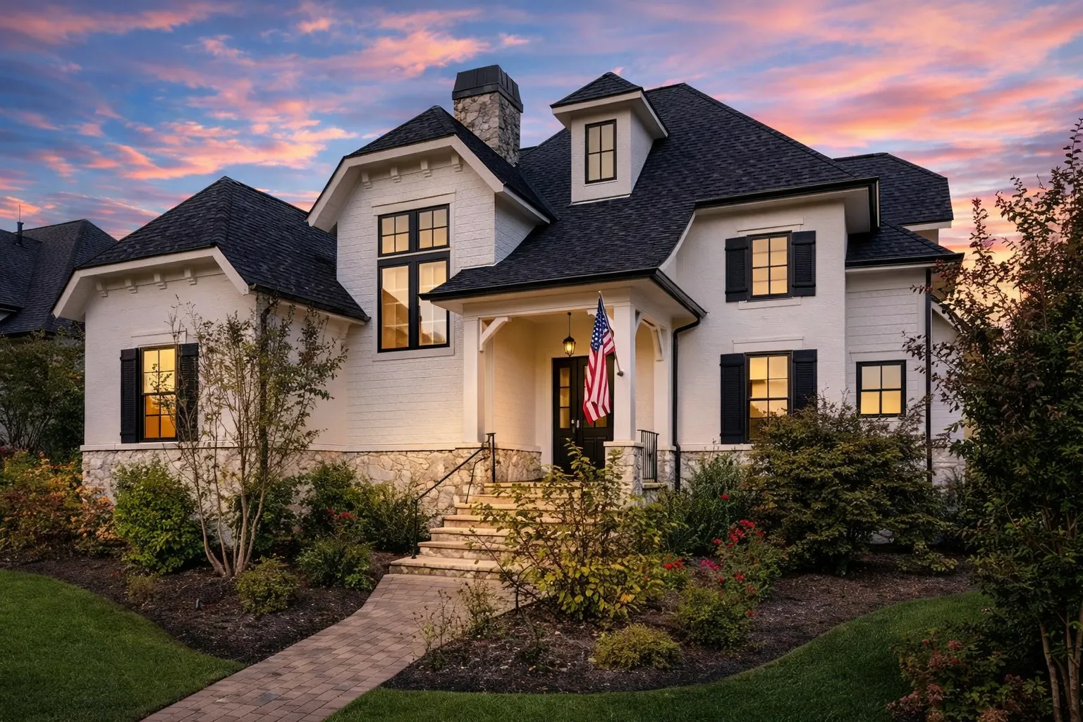 Front elevation of a French Country style luxury home featuring stone and stucco exterior, steep hipped roof, arched entry, and classic European detailing