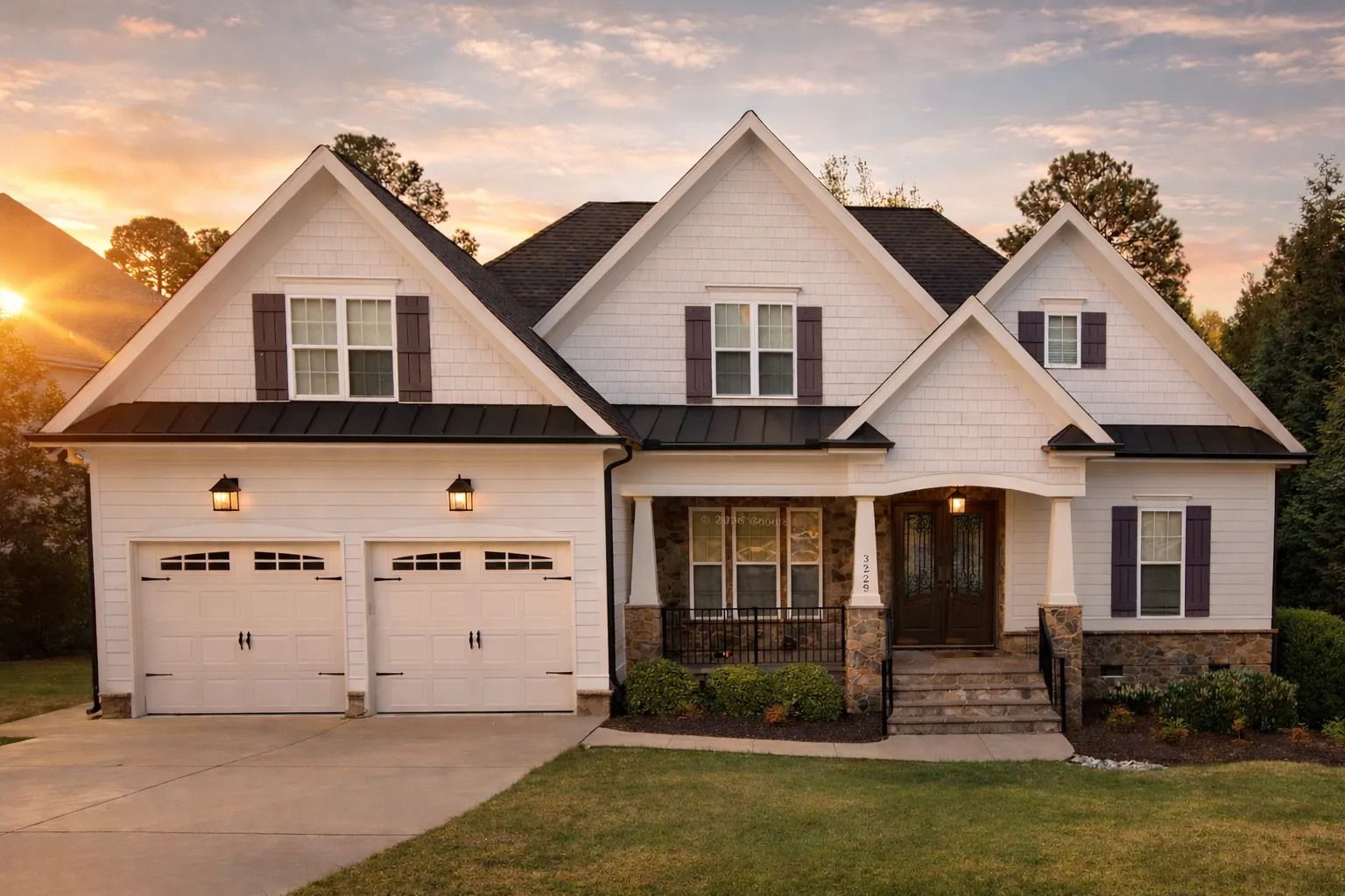 Front exterior view of a Modern Farmhouse style home with white lap siding, stone accents, black metal roof details, and covered front porch