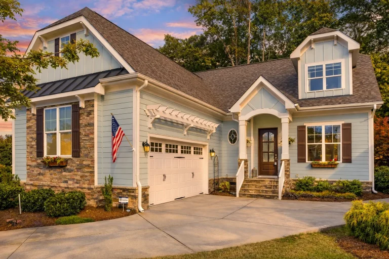Front elevation of a Cape Cod cottage style home featuring lap siding, board-and-batten gables, stone accents, and a welcoming front entry