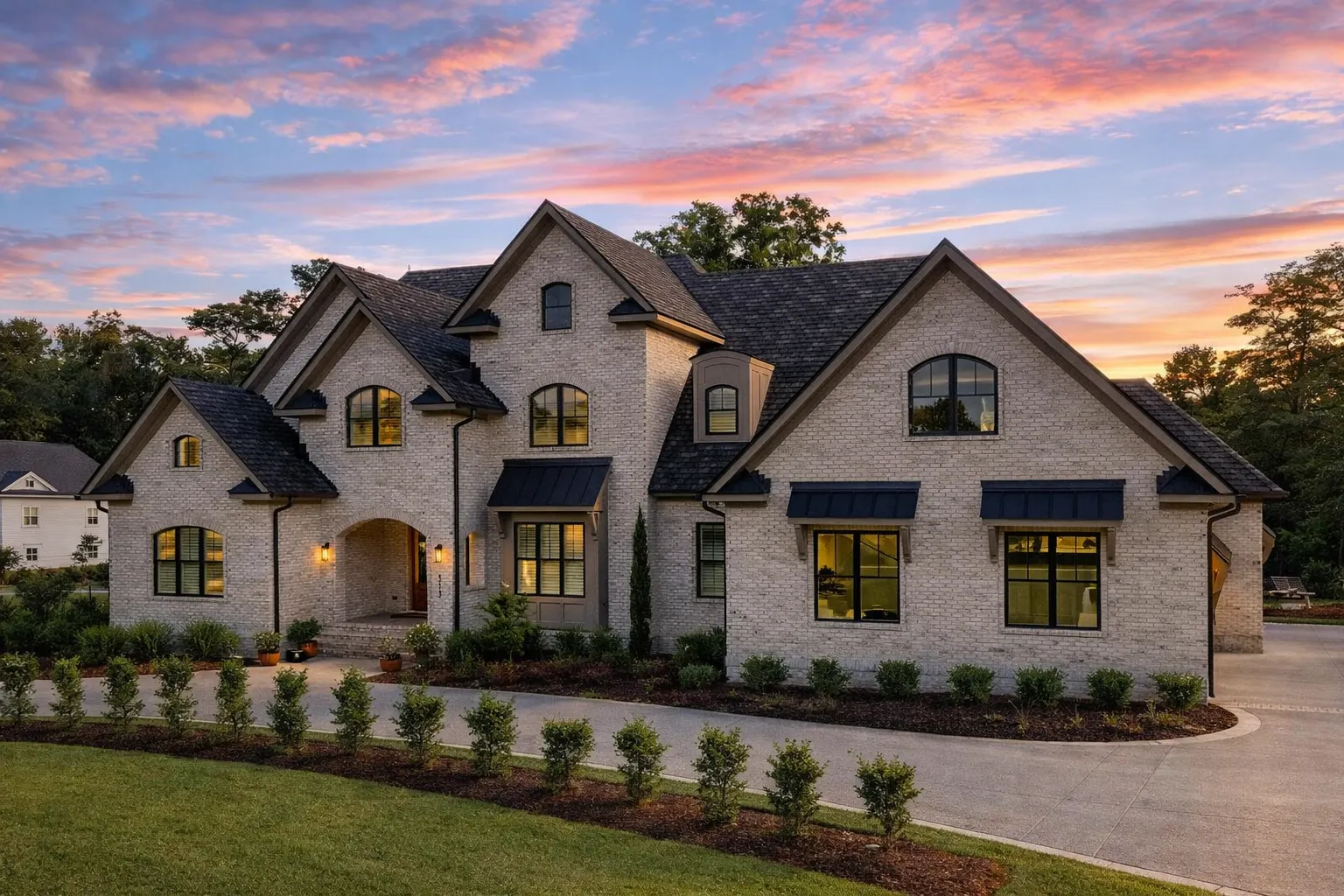 Front elevation of a Modern Traditional New American house with painted brick exterior, steep gables, metal awnings, and symmetrical upscale curb appeal