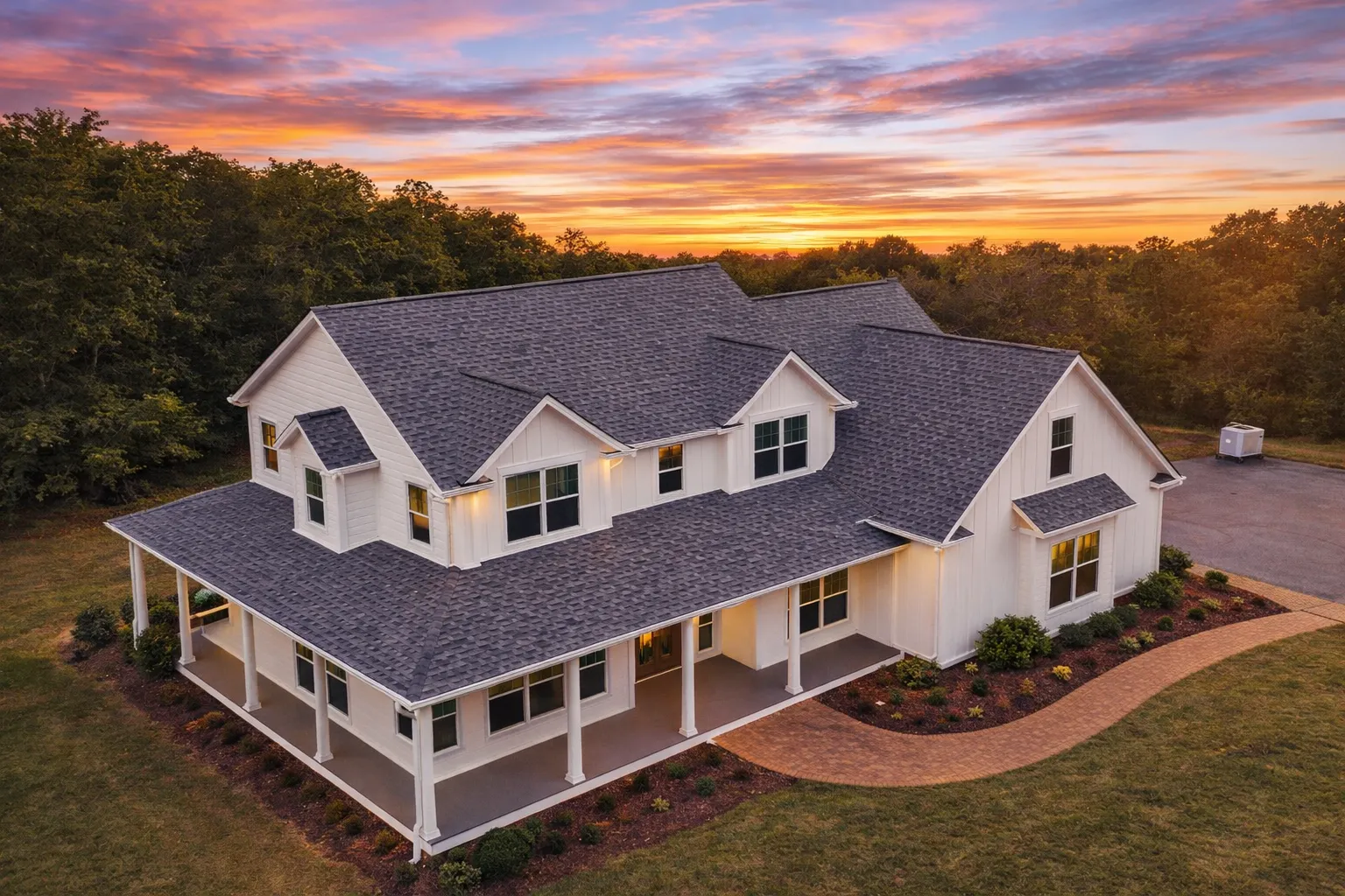 Front view of Modern Farmhouse with white board and batten siding, dark roof, and stone foundation accents