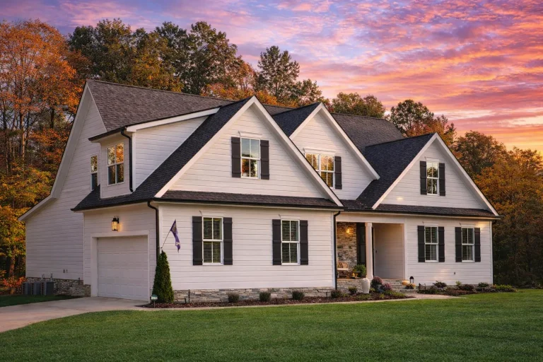 Front elevation of a Cape Cod style home featuring horizontal siding, stone wainscot, symmetrical gables, and an attached garage