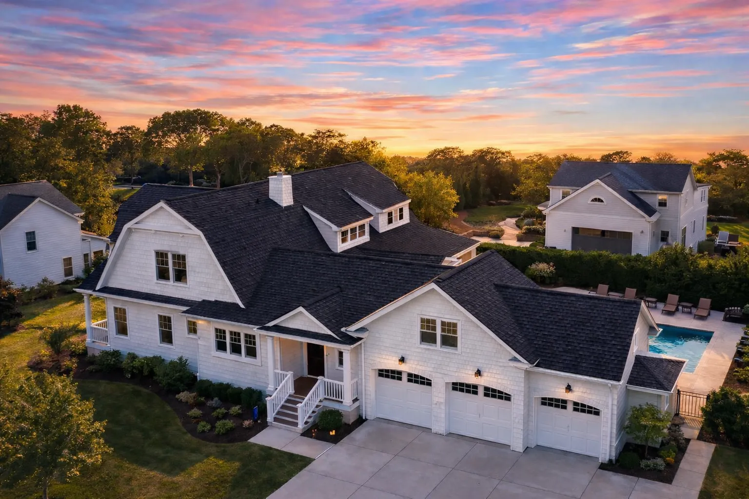 Front elevation of a Shingle Style Cape Cod home with white cedar shake and horizontal lap siding, symmetrical dormers, and a covered entry porch