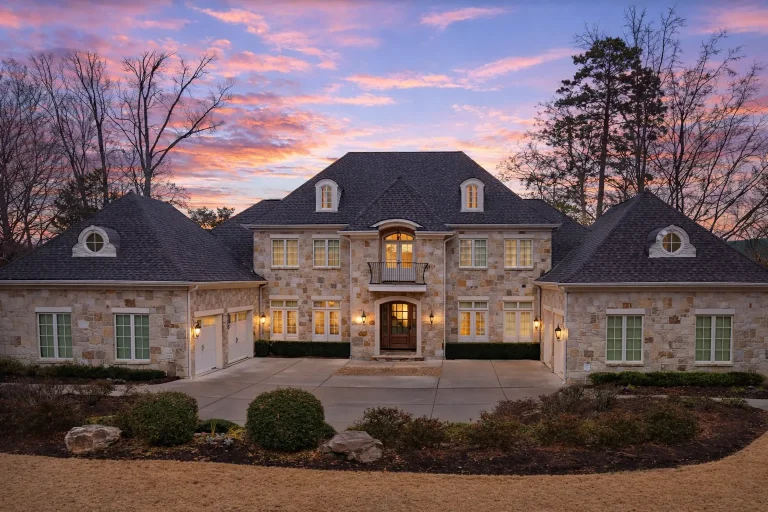 Front elevation of a French Country European Traditional estate home featuring brick exterior, stone accents, steep hipped roof, dormers, and symmetrical façade
