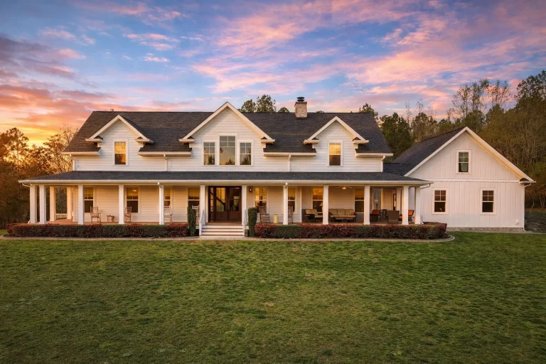 Front elevation of a Southern Farmhouse style home with board and batten siding, wide wraparound porch, symmetrical façade, and classic farmhouse detailing