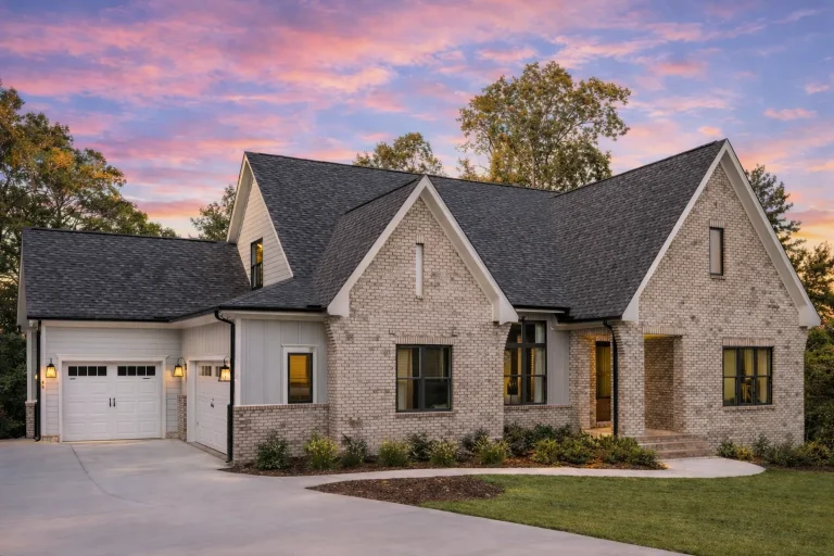 Front elevation of a modern farmhouse style home with board and batten siding, gabled rooflines, dark window trim, and an attached garage