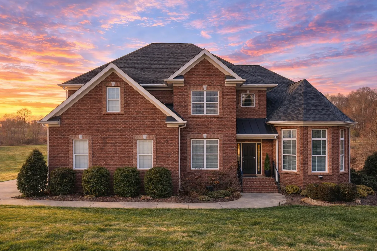 Front elevation of a Traditional Colonial style home featuring a full brick exterior, symmetrical façade, and gabled rooflines under a clear blue sky