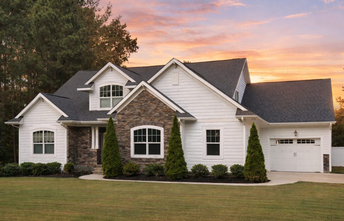 Front elevation of a New American style home featuring horizontal lap siding, stone accents, gabled rooflines, and an attached garage