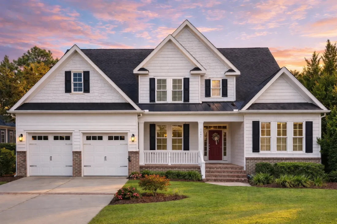Front exterior view of a Traditional Colonial style home with red brick facade, horizontal siding, gabled rooflines, and attached two-car garage