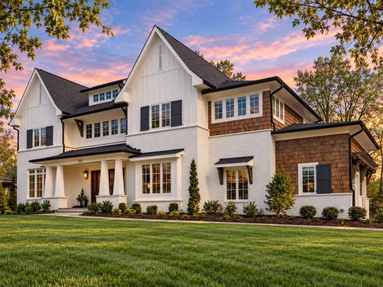 Front view of a Modern Farmhouse style home featuring a blend of stone and board and batten siding with gabled rooflines and black-framed windows