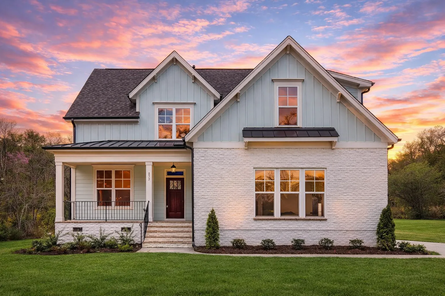 Front view of Modern Farmhouse style home featuring board and batten siding, brick accents, and a welcoming covered porch entry