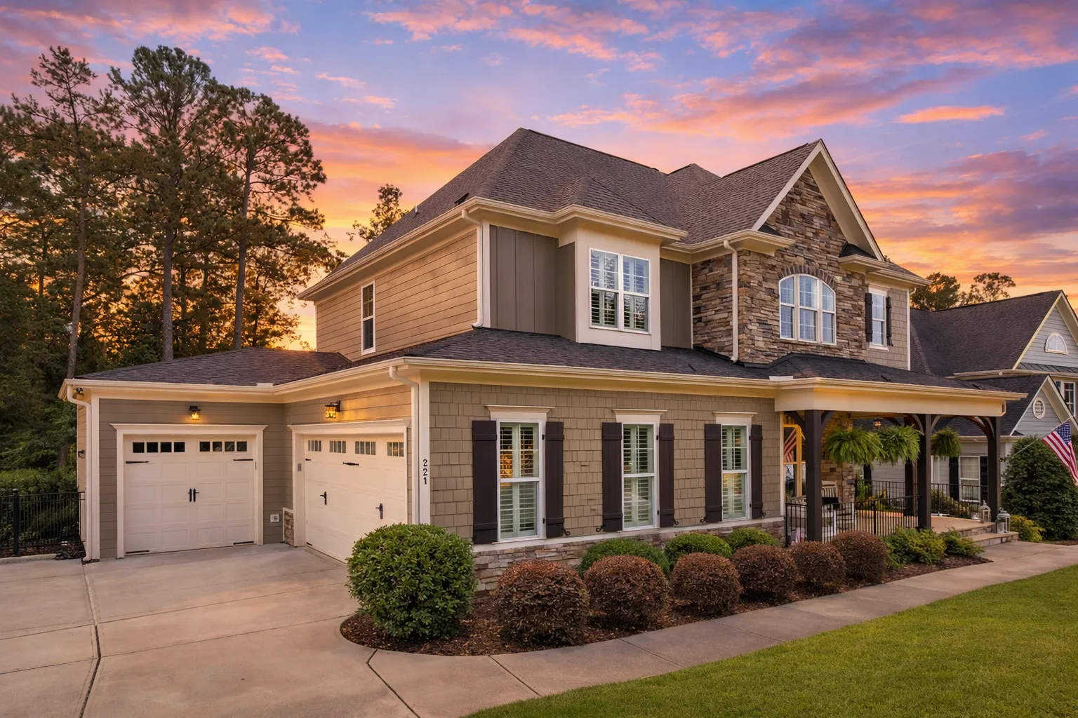 Front elevation of a two-story New American modern traditional home with stone veneer, horizontal lap siding, covered porch, arched entry, and front-entry garage