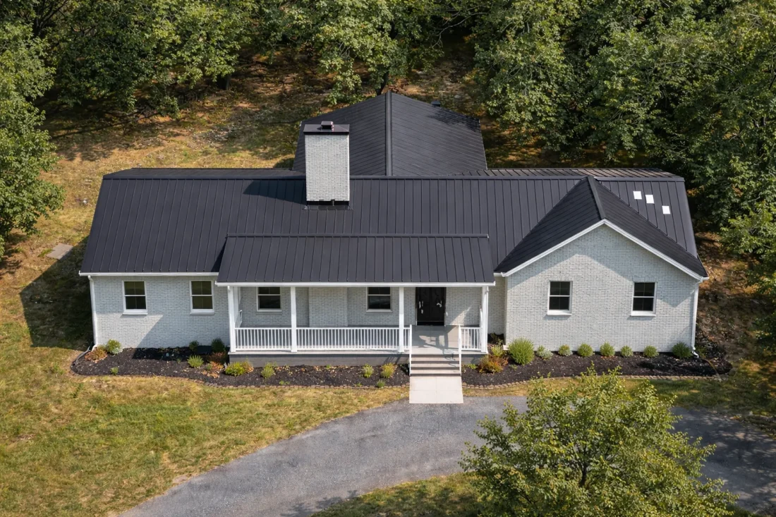 Front elevation of a Traditional Ranch style home featuring horizontal siding, stone accents, metal roof, and a welcoming covered porch