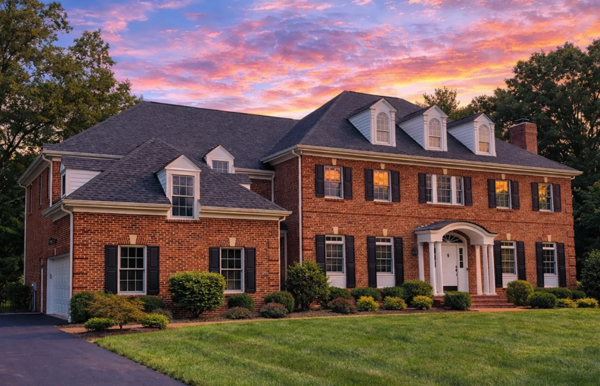 Front elevation of Georgian Colonial style home with red brick exterior, black shutters, dormer windows, and formal symmetrical architecture