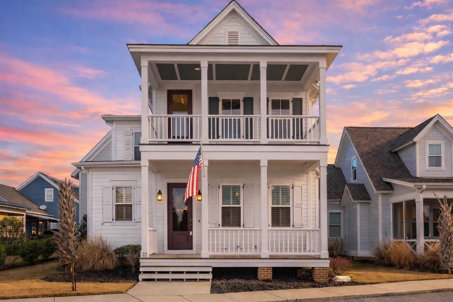 Front elevation of a Coastal Colonial style home featuring horizontal lap siding, symmetrical façade, and stacked covered porches