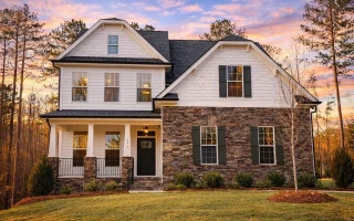Front elevation of a New American style house featuring stone exterior, shake siding, white trim, and covered front porch