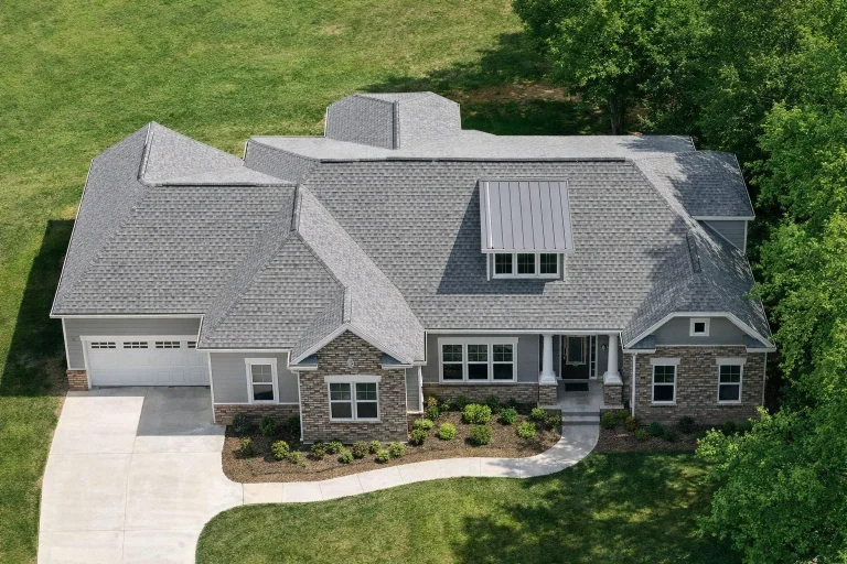 House Plans with Home Office 1 Front exterior of a New American ranch style house featuring stone veneer, board and batten siding, metal porch roof, and warm interior lighting at sunset