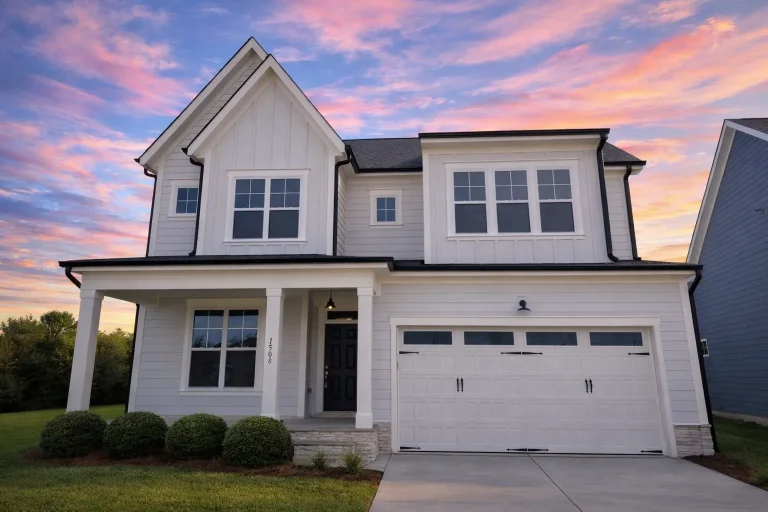 Front elevation of a modern farmhouse style two-story home featuring board and batten siding, stone accents, black windows, and a front-entry garage