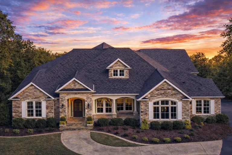 Front elevation of a Traditional New American style home featuring stone and brick exterior, arched windows, and symmetrical curb appeal