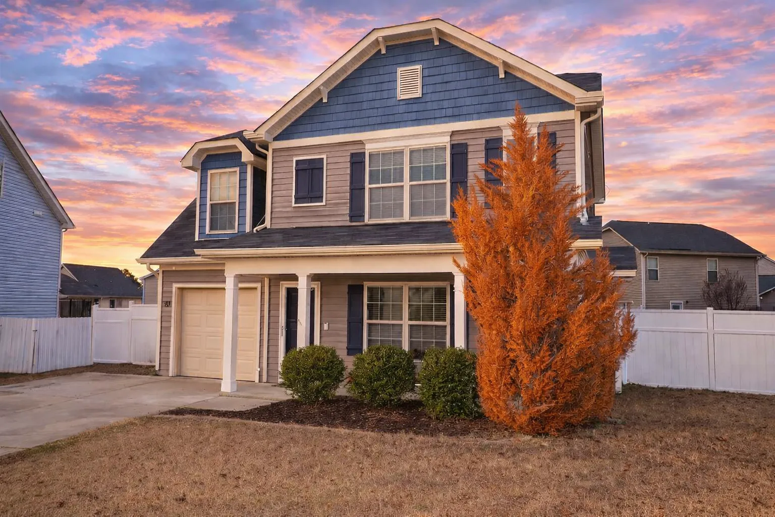 Front view of a Traditional Colonial style house featuring horizontal siding, stone base, red shutters, and a one-car garage with covered porch entry.