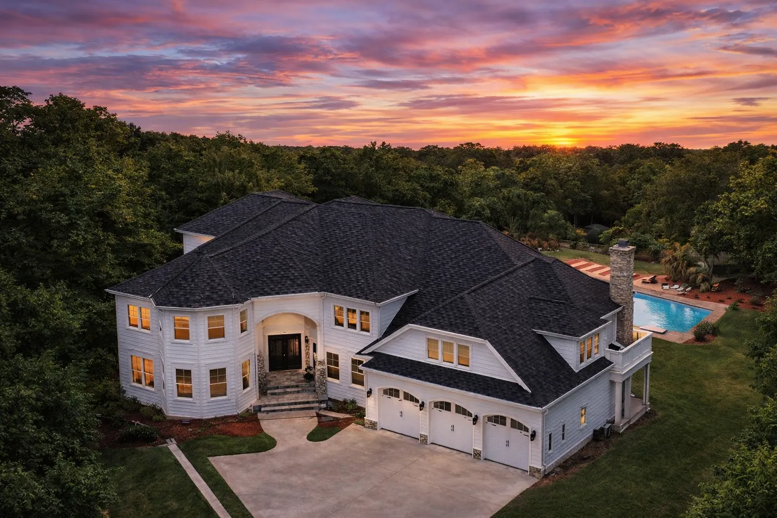 Front exterior view of a New American style luxury home with smooth stucco exterior, multi-gable rooflines, arched entry, and side-entry garage