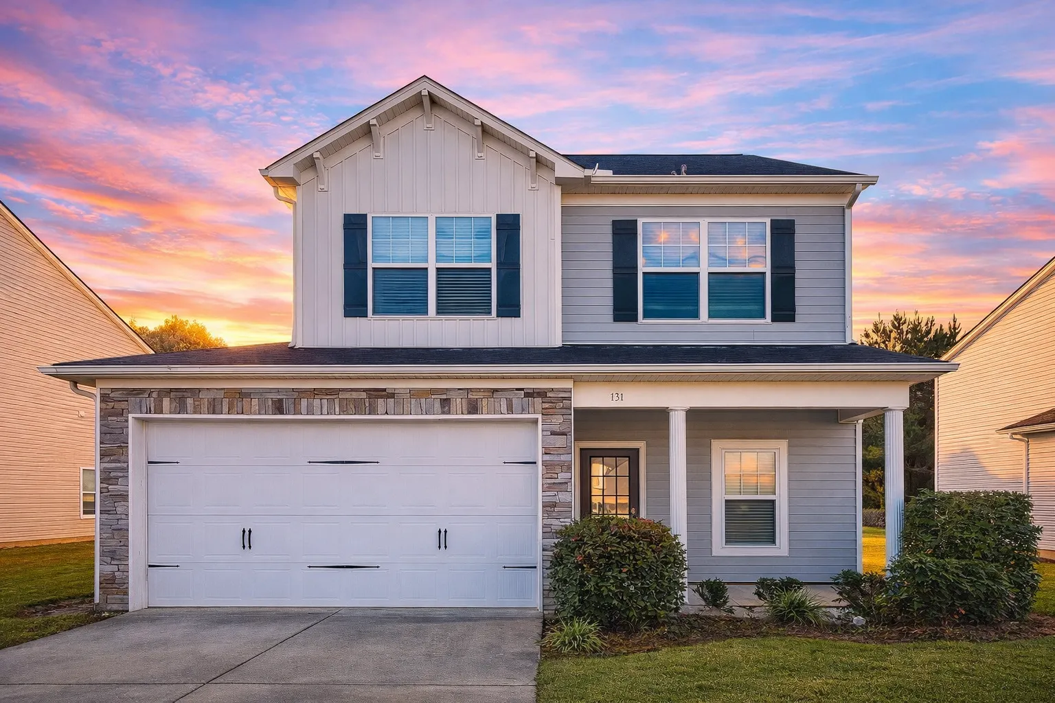 Front elevation of a two-story Traditional Colonial style home with stone and horizontal siding exterior, symmetrical windows, and double garage