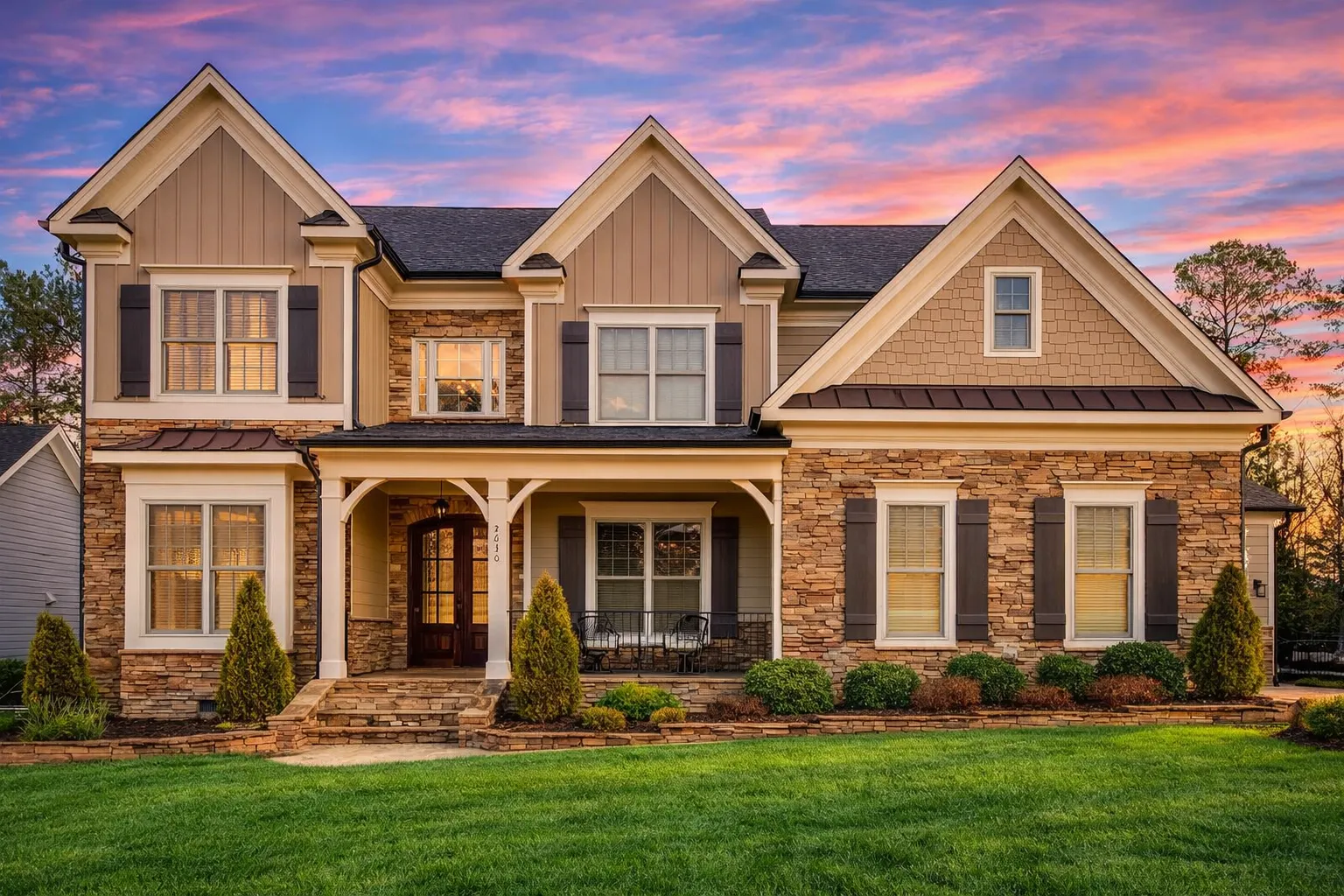 Front elevation of a New American Traditional style home featuring stone accents, horizontal siding, and a symmetrical two-story design