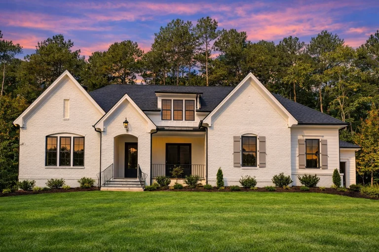 Front elevation of a Modern Farmhouse style home with smooth white stucco exterior, black-framed windows, gabled rooflines, and covered entry porch