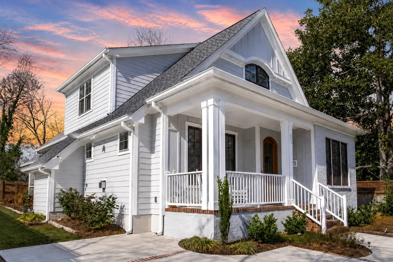 Front elevation of a Traditional Colonial style home with brick exterior, board and batten gable accent, symmetrical windows, and covered entry porch