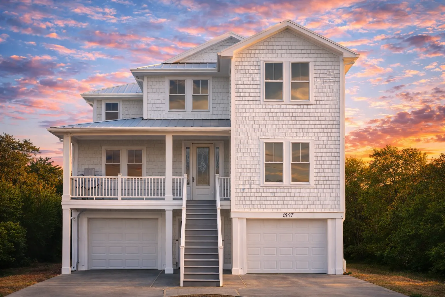 Front elevation of a Coastal Traditional home with elevated foundation, horizontal siding, shingle accents, double garages, and a covered front porch