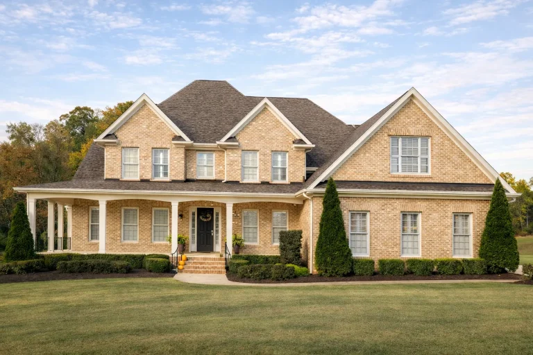 Front exterior view of a Traditional Colonial style home with red brick exterior, white trim, symmetrical facade, and covered front porch