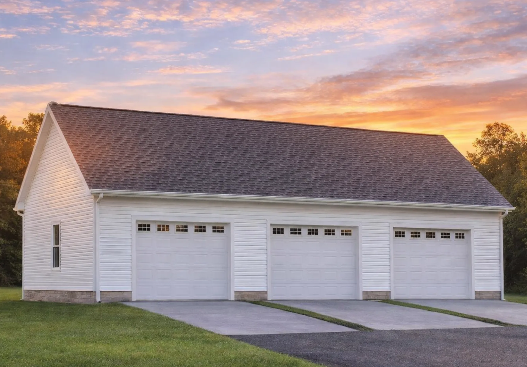 Front elevation of a traditional three-car garage with horizontal siding, brick accents, and gable roof