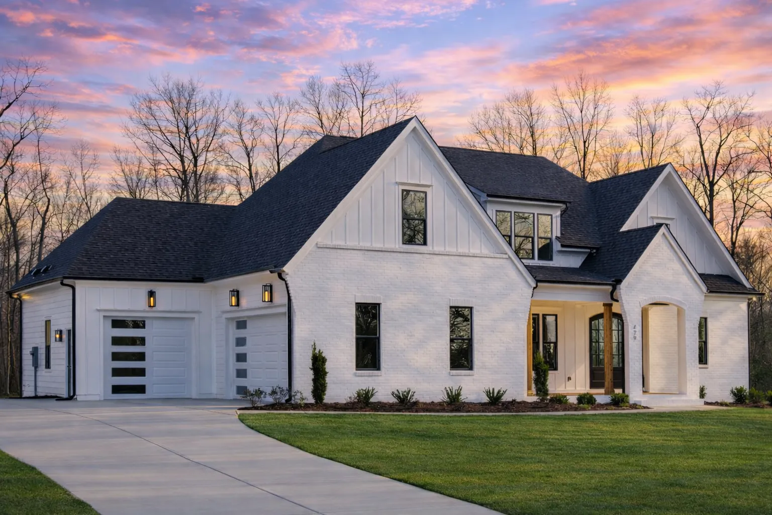 Front exterior view of a New American modern traditional house with painted brick walls, board and batten gables, steep rooflines, and side-entry garage