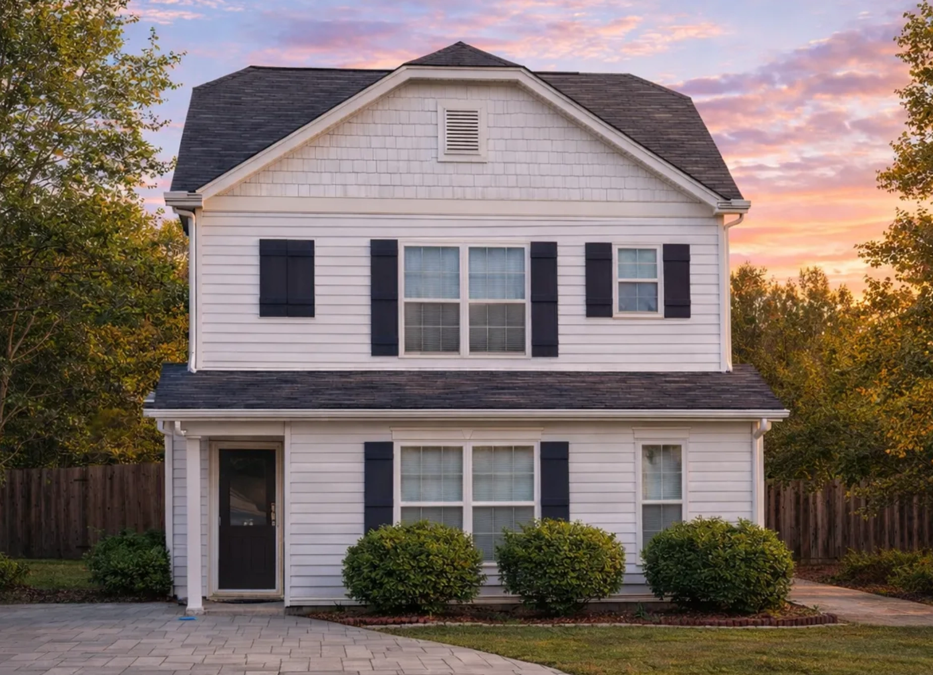 Front elevation of a Traditional Colonial Suburban style home featuring gray horizontal siding, red shutters, symmetrical windows, and classic covered porch entry