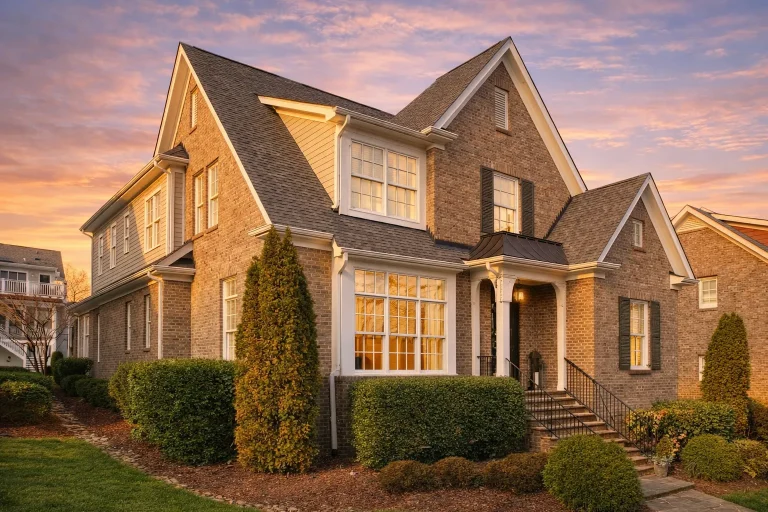 Front elevation of a Traditional Colonial style brick home with symmetrical windows, black shutters, steep gabled roof, and centered entry
