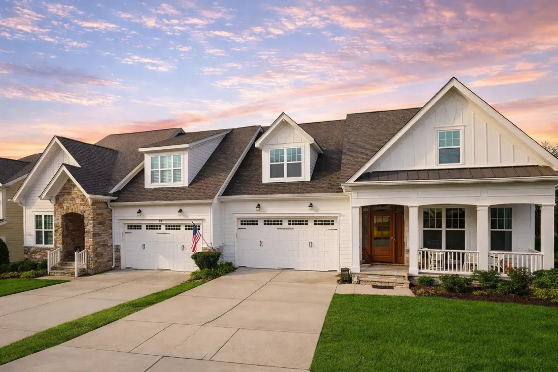 Front elevation of New American Modern Traditional house with brick exterior, board and batten accents, gabled rooflines, and three-car garage