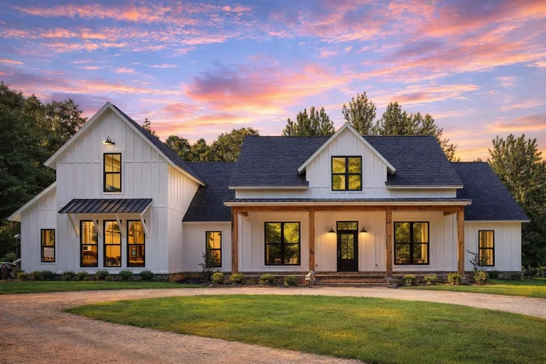 Front elevation of modern farmhouse home with white board and batten siding, black windows, gabled rooflines, and covered front porch