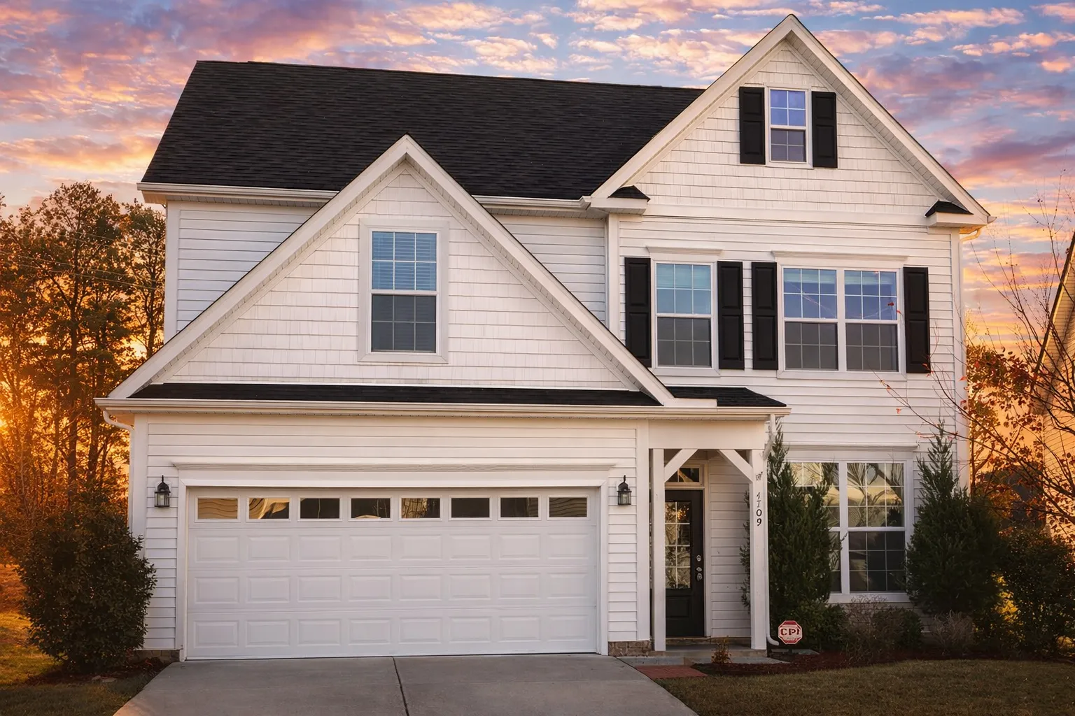 Front elevation of a Traditional Colonial home featuring gray horizontal siding, shingle gable accents, brick base, and symmetrical two-story façade with modern detailing.